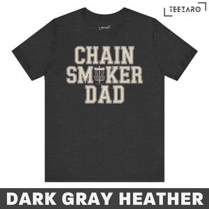 May include: Dark gray heather t-shirt with the text "Chain Smoker Dad" in white with a disc golf disc graphic.