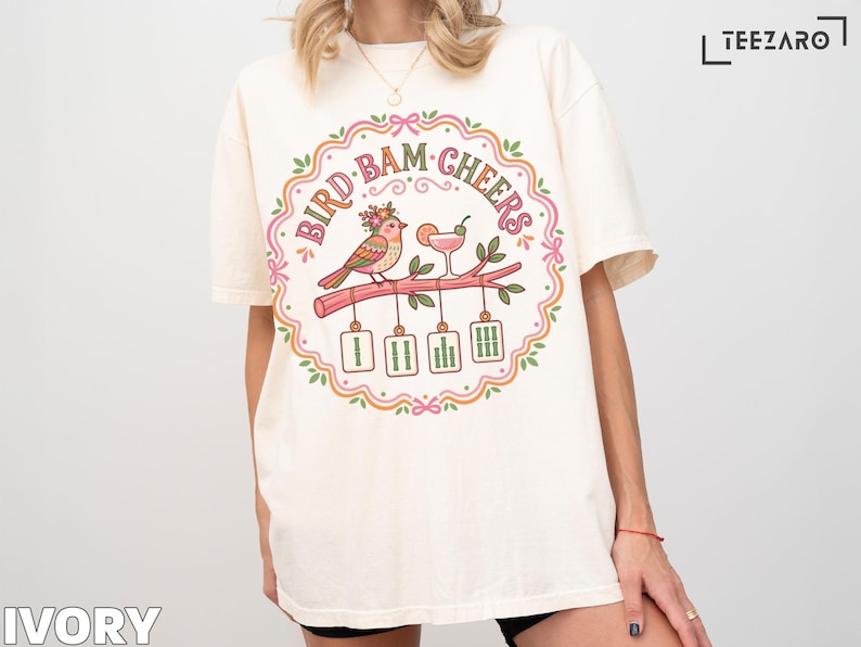 Cream t-shirt with "BIRD BAM CHEERS" text and bird on branch graphic.