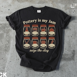 Puede incluir: Una taza de cerámica blanca con asa negra y el texto "But First, Coffee" en negrita negra. La taza se encuentra sobre un fondo borroso, sugiriendo un ambiente acogedor.