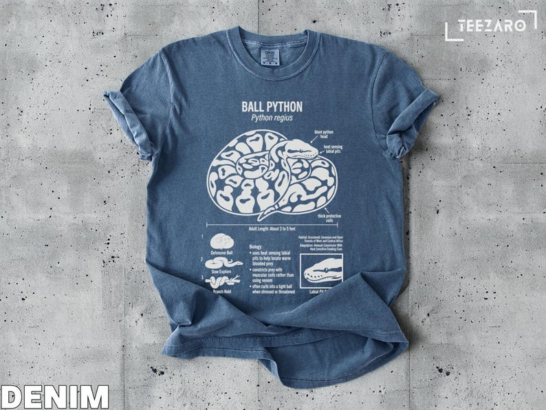Ball python illustration on a denim t-shirt with text describing its biology and habitat.