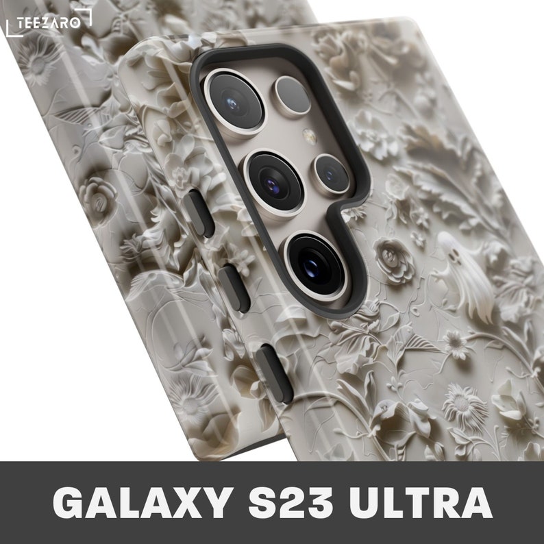 Puede incluir: Una funda de tel&eacute;fono blanca con un dise&ntilde;o floral detallado. La funda est&aacute; dise&ntilde;ada para el Galaxy S23 Ultra.