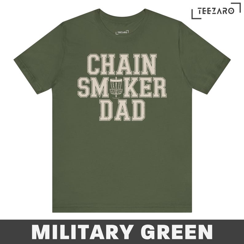 May include: A military green t-shirt with the text "Chain Smoker Dad" in a white vintage font. A disc golf disc is featured in the text.