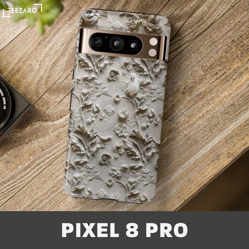 Puede incluir: Una funda de tel&eacute;fono blanca con un dise&ntilde;o floral en relieve 3D y un fantasma. La funda es para un tel&eacute;fono Pixel 8 Pro.