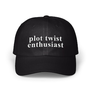 Puede incluir: Gorra de béisbol negra con el texto blanco "plot twist enthusiast". La gorra tiene una visera curva y una corona estructurada. Un accesorio casual para el uso diario.
