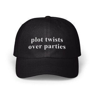 Puede incluir: Gorra de béisbol negra con el texto blanco "plot twists over parties". La gorra tiene una visera curva y un cierre de correa de tela en la parte trasera. Un sombrero de estilo clásico, adecuado para uso casual.