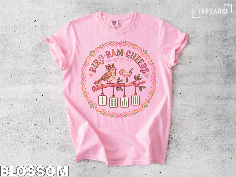 Pink t-shirt with "Bird Bam Cheers" text, a bird on a branch, and cocktails.