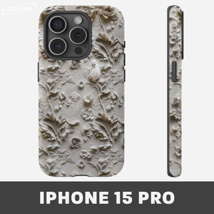 Puede incluir: Una funda blanca para iPhone 15 Pro con un dise&ntilde;o floral en relieve 3D. El dise&ntilde;o presenta flores blancas, hojas y un fantasma.