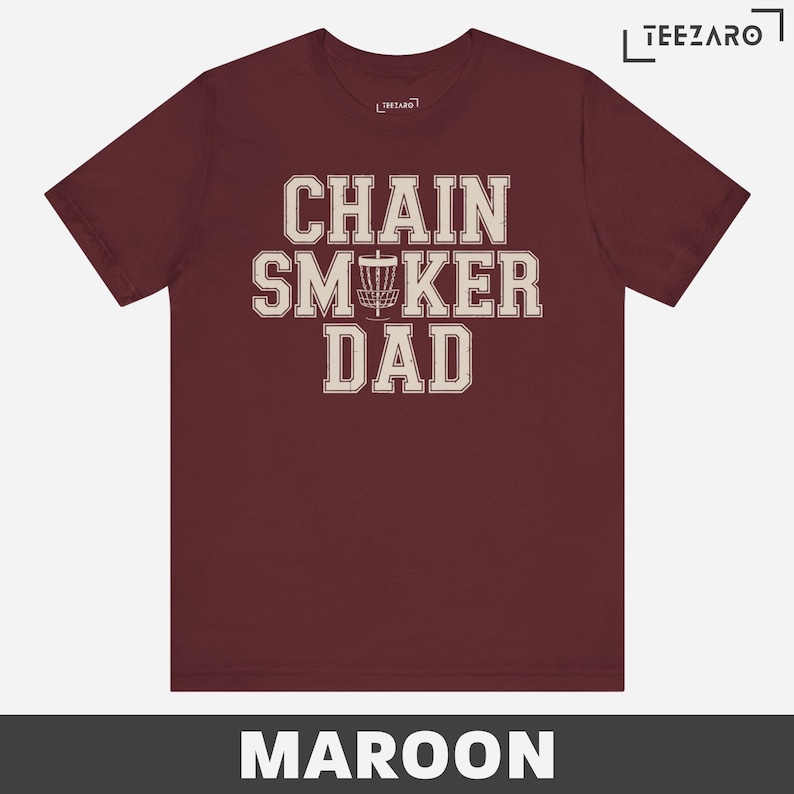 May include: Maroon t-shirt with the text "Chain Smoker Dad" in white with a disc golf disc graphic.