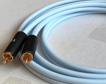 May include: Light blue audio interconnect cable with black connectors and gold-colored tips. The cable is coiled and features the text "Analog Interconnect Cable" and "Made in Sweden CE".