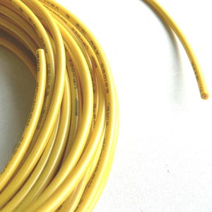 May include: A coil of bright yellow electrical wire against a white background. The wire is labeled with text including "AWM 1015" and "UP-000". The wire is flexible and appears to be new.