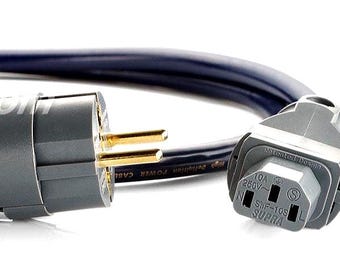 May include: A dark blue power cable featuring a gray Schuko plug with gold-plated pins and a gray IEC C13 connector. The cable is marked with the text Supra and includes technical specifications printed in white along its length.