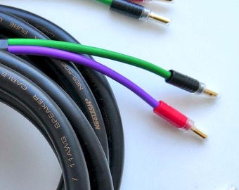 May include: Black speaker cable with colored connectors. The cable is coiled, with text that reads "SPEAKER CABLE" and "NEOTECH". The connectors are red, black, and green, with gold-colored tips. The cable is designed for lower voltage use.