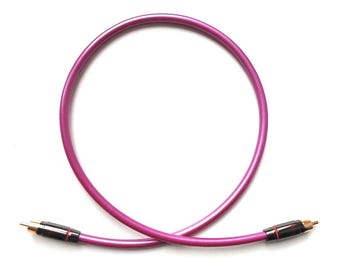 May include: A vibrant magenta audio cable with gold-colored connectors. The cable is curved in a circular shape against a white background. The connectors have black and red accents.