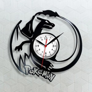 Op de afbeelding: Zwarte vinylplatenklok met een drakenontwerp en het woord "Pokemon" onderaan. De klok heeft een witte wijzerplaat met zwarte cijfers en wijzers, en een rode secondewijzer. De draak is zwart silhouet.