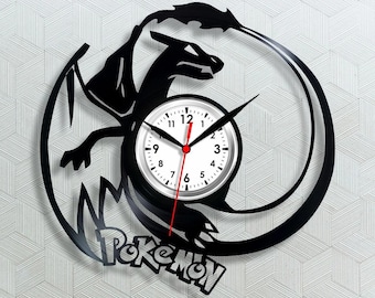 May include: Black vinyl record clock featuring a dragon design with the word "Pokemon" at the bottom. The clock face is white with black numbers and hands, and a red second hand. The dragon is silhouetted in black.
