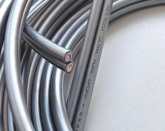 May include: A coiled length of silver-colored Neotech NES-5004 Ultra Pure UPOFC 2 x 4.05 speaker cable. The cable features a smooth, rounded exterior casing and two exposed copper wire ends showing the internal conductive strands clearly.
