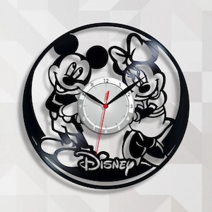 May include: Black and white wall clock featuring Mickey and Minnie Mouse. The clock has a silver face with black hands and a red second hand. The word "Disney" is at the bottom.