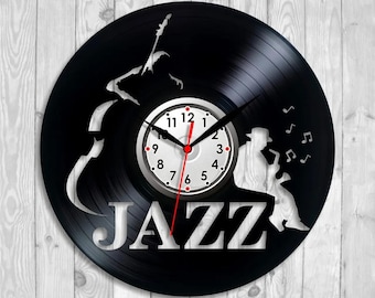 May include: Black vinyl record clock with a white clock face and red second hand. The word "JAZZ" is cut out of the record. A silhouette of a musician playing a saxophone is on the right side of the clock.