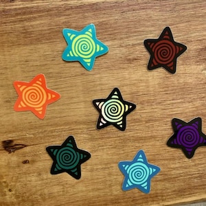May include: Seven star-shaped stickers, each featuring a central spiral design. The stickers are colored in bright yellow-green, dark red, orange, black with a yellow spiral, dark green, purple, and light blue, all with contrasting spiral lines.