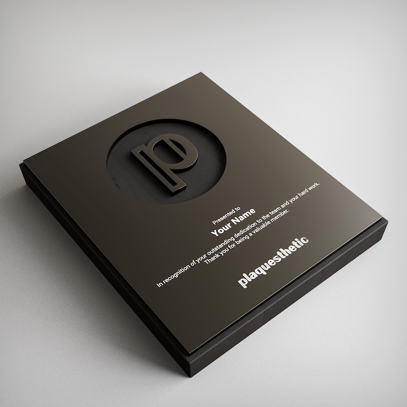May include: A black plaque with a raised letter "P" inside a circle. The plaque reads "Presented to Your Name" and "plaquesthetic" in white text. The plaque is rectangular and has a matte finish.