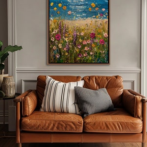 Puede incluir: Pintura al &oacute;leo de una escena costera con cielo azul y mar. El primer plano presenta una playa de arena con coloridas flores silvestres en tonos rosa, amarillo y morado. La obra est&aacute; enmarcada en un marco de madera marr&oacute;n.