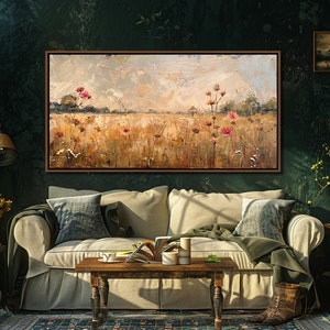 May include: A painting of a field with wildflowers in shades of pink and white, set against a backdrop of a cloudy sky. The painting is framed in a dark wood frame and hangs on a dark green wall in a living room setting.