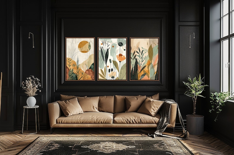 May include: Three framed abstract art prints with a nature theme. The prints feature a mix of green, brown, orange, and yellow colours. The prints are hung on a black wall above a brown sofa.