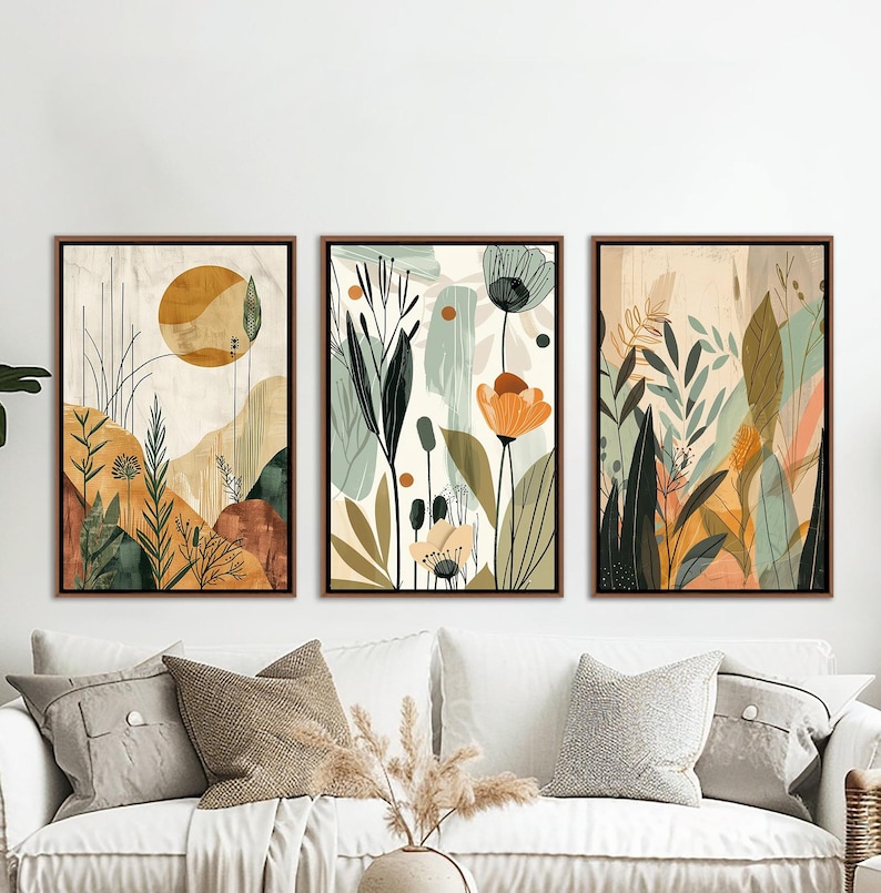 May include: Three abstract floral prints in a minimalist style. The prints feature a muted colour palette of green, brown, and orange. The prints are framed in a natural wood frame.