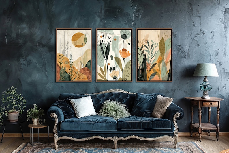 May include: Three framed abstract art prints with a nature theme. The prints feature a variety of colours, including green, blue, yellow, and orange. The prints are arranged in a row on a wall, above a blue velvet sofa.