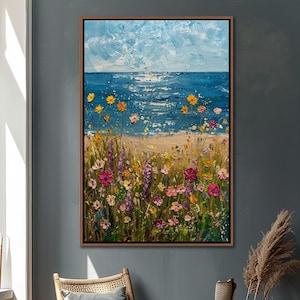 Puede incluir: Una pintura al &oacute;leo de una escena de playa con una vibrante exhibici&oacute;n de flores silvestres. La obra presenta un oc&eacute;ano azul bajo un cielo nublado, con una orilla arenosa y flores coloridas en primer plano. La pintura est&aacute; enmarcada en un marco de madera marr&oacute;n.