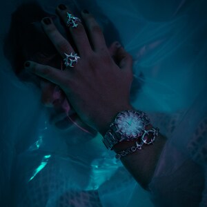 Puede incluir: Un reloj de pulsera plateado con una esfera blanca y agujas negras. El reloj tiene una correa plateada con un brazalete de cadena plateada unido a &eacute;l. El reloj se lleva en la mu&ntilde;eca de una persona.