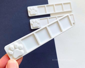May include: White plastic palette with five paint wells and a paw print design. The palette is designed for holding small amounts of paint.