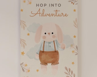 May include: A rectangular wall art print featuring a light-colored background with the text "HOP INTO Adventure" in dark gray and orange. A central illustration depicts a light pink rabbit wearing a blue striped shirt and brown shorts.