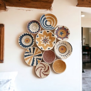 May include: A wall decor set of 10 round woven baskets with geometric patterns in shades of brown, tan, and blue. The baskets are arranged in a circular pattern on a white wall.