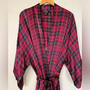 May include: A red, black, and navy plaid robe with a matching belt. The robe is hanging on a wooden hanger. The robe has a classic plaid pattern and a relaxed fit.
