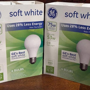 May include: Two boxes of GE soft white light bulbs. Each box displays a 75W incandescent replacement, using only 53W. The boxes feature a white bulb graphic and text indicating 28% less energy use than 75W bulbs. The boxes contain 4 bulbs.