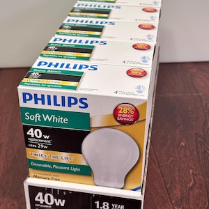 May include: A stack of Philips Soft White light bulb boxes, each featuring a 40-watt replacement label, 29-watt energy usage, and a 28% energy savings graphic. The packaging displays the text Twice The Life, Dimmable, Pleasant Light, and Mercury Free.