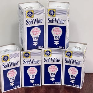 May include: A collection of six boxes of GE Soft White light bulbs. Each box is white with blue accents and features the GE logo, the words "Soft White", and "Soft Pleasing Light". The boxes also indicate the bulbs are 150 watts.