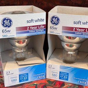 May include: Two GE soft white 65W indoor spotlight bulbs in their original packaging. Each box displays the GE logo, bulb specifications, and the text "2 Year Life". The boxes are white with blue and red accents.