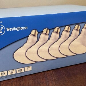 May include: A blue box of Westinghouse 65W flood light bulbs. The box features the Westinghouse logo and contains six light bulbs. The box also displays the light output, energy usage, and life hours of the bulbs.
