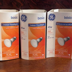 May include: Three white cardboard boxes of GE Basic Indoor Floodlight bulbs. Each box has a 45W bulb, 350 lumens, and a 1.4-year life. The boxes have an orange and white design with the GE logo.