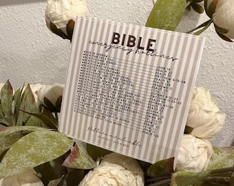 May include: A beige and white Bible emergency hotlines card with a list of Bible verses for various situations. The card is surrounded by white and green floral accents. The text "Hollie available" and "24 hours 7 days a week" is also visible.