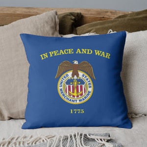 May include: Blue throw pillow with the words "In Peace and War" and the United States Merchant Marine seal with an eagle and anchor. The seal is surrounded by the words "United States Merchant Marine" and the year "1775".
