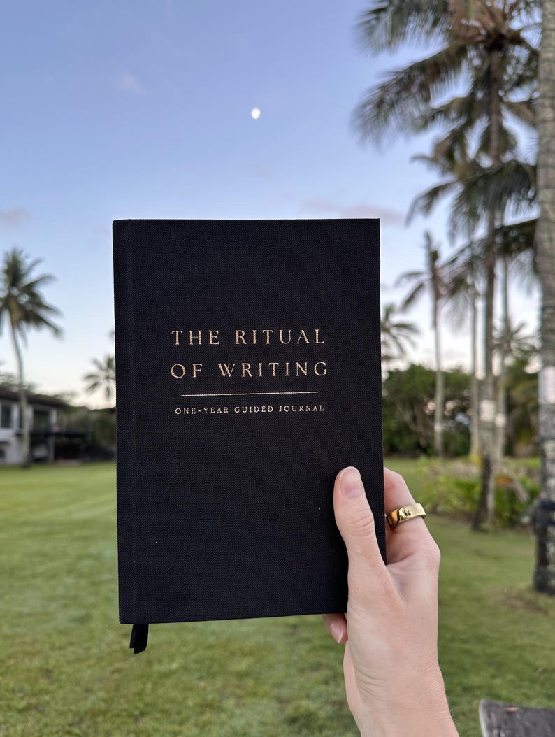 May include: A black journal with gold lettering that reads "The Ritual of Writing" and "One-Year Guided Journal".