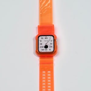 May include: Orange clear plastic watch band with a silver buckle and a clear orange case with a white watch face that says "TUE 12" and has Roman numeral markings.