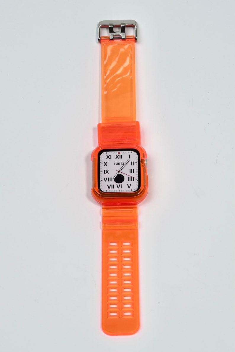May include: Orange clear plastic watch band with a silver buckle and a clear orange case with a white watch face that says "TUE 12" and has Roman numeral markings.