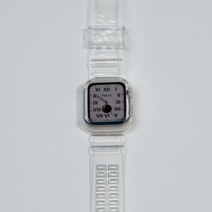 May include: A clear plastic watch band with a silver buckle and a clear plastic watch face with Roman numeral markings. The watch face displays the date "TUE 12".