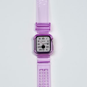 May include: A clear purple watch band with a silver buckle and a clear purple case with a white watch face that says "TUE 12" and has Roman numerals.