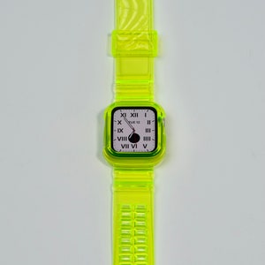 May include: A bright yellow clear plastic watch band with a white watch face that displays the time and the day of the week. The watch face reads "TUE 12".