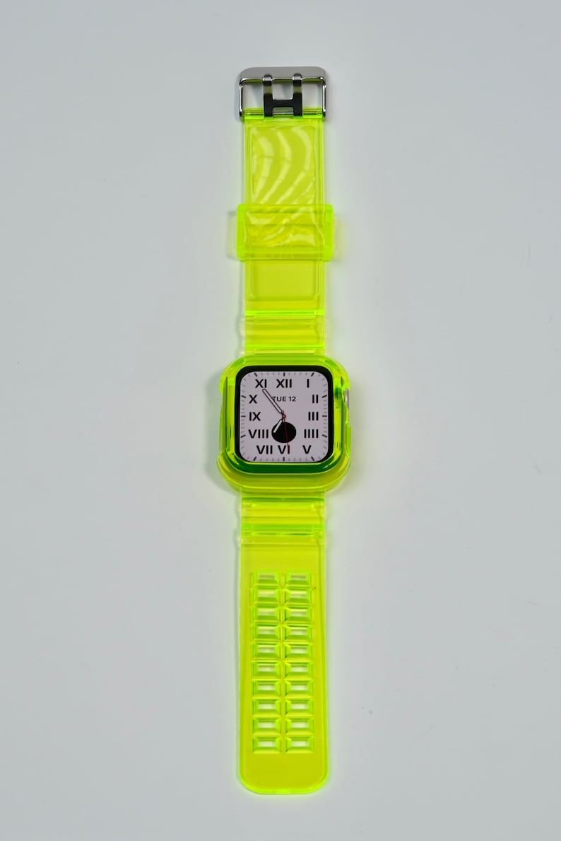 May include: A bright yellow clear plastic watch band with a white watch face that displays the time and the day of the week. The watch face reads "TUE 12".
